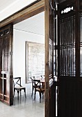 Filigrane Holzstühle in Essraum mit großem Wandgemälde; im Vordergrund eine antike, chinesische Holztrennwand mit großer Flügeltür
