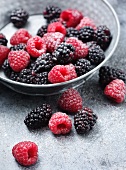 Sugared raspberries and blackberries in and in front of a bowl