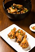 Asian Style Chicken Drumettes on a Platter; Chicken in Bowl in Background