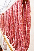 Fresh salsiccia sausages hanging on a bamboo rack
