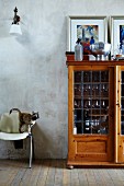 Display cabinet used as bar with bar equipment on top against patchy wall; cat on chair ready to jump