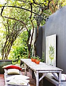 Rustic seating area with furniture made from logs against grey-painted terrace wall