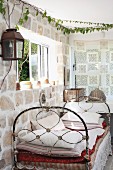 Vintage daybed below window in stone wall in corner of rustic interior