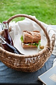 A picnic basket with a sandwich and drinks