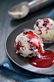 Two scoops of blackberry and blueberry ice cream with fruit sauce