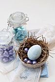 Mini chocolate eggs in preserving jars and a painted egg in a nest for Easter