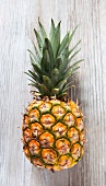 A pineapple on a wooden slap, viewed from above