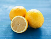 Whole and half lemons on a blue surface