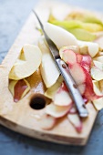 Geschälte Äpfel und Birnen, Apfelschale und Birnenschale auf einem Holzbrett