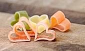 Colourful heart-shaped pasta pieces on a wooden table