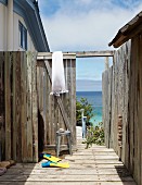Flippers in weathered outdoor shower area; view of sea through open gate