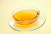 A glass teacup of yellow tea