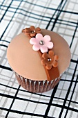 A chocolate cupcake with caramel filling, topped with fondant icing