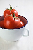 Several tomatoes in an enamel cup