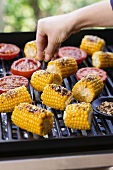 Corn on the cob being seasoned on the barbecue