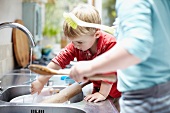 Kinder waschen Geschirr zusammen