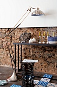 Ornaments on console table, stainless steel standard lamp, basketwork side table and Dutch-style floor tiles