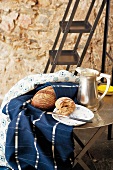 Blau-weiss gemusterte Tischtücher, Silberkanne und holländischer Teller mit Brot auf Metalltisch