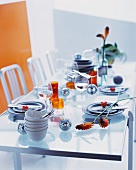 A glass table laid with glasses, bowls, floral decorations and disco balls