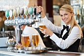 A waitress pouring draught beer in a pub
