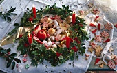 Weihnachtskranz aus Stechpalme und Efeu mit Kerzen, gefüllt mit Keksen (Vanillekipferl, Pecankugeln, Ingwer-Kokos-Makronen)