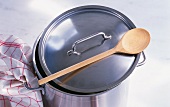 A saucepan with a wooden spoon and a tea towel