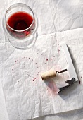 Half Empty Glass of Red Wine with Corkscrew and Wine Stains on Paper
