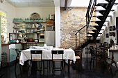 Exposed stone wall, interior staircase, kitchenette and dining table in kitchen