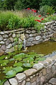 Wasserbecken aus Naturstein mit Terrakotta-Tierkopf als Wasserspeier und blühenden Seerosen