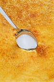 A spoon stuck in the sugar crust on a crème brûlée