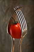 A small tomato between two forks