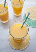 Three glasses of orange juice with blue and white striped drinking straws