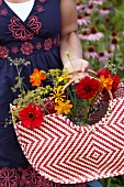 Frau sammelt Sommerblumen in einer Tasche
