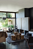 Stools made from sections of tree trunk in front of fireplace in living room with walls painted dark grey