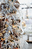 Weihnachtsbaum aus Holz und weiss gefärbten Farnblättern mit Lichterkette