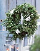 Winter wreath of juniper with Christmas-tree-shaped decorations on terrace