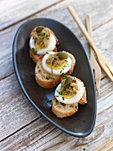 Mini open sandwiches topped with egg, anchovy paste and capers