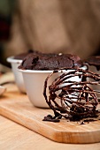 Schokoladenkuchen mit flüssigem Kern; im Vordergrund ein Schneebesen mit Teigresten