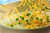 Pasta and peas falling into a casserole dish