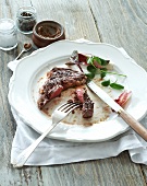 Remains of a meal of beef steak with salad leaves, mustard, salt and pepper