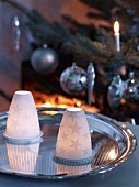 Windlichter mit Porzellanhaube und Sternenmotiv auf Silbertablett vor Weihnachtsbaum
