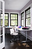 Modern workspace in corner of room with black, traditional lattice windows