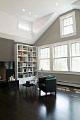 Moderner Sessel und weisses Regal vor grauer Wand und dunkler Holzboden in ausgebautem Dachgeschoss mit traditionellem Flair