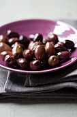 Schwarze Oliven auf violettem Teller