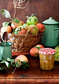 A Jar of Yellow Tomato and Apple Chutney on a Table with a Basket of Fresh Apples