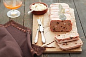 Meat terrine with raisins, wrapped in bacon, on a wooden board