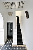 Verschmelzung von marokkanischer Tradition und Moderne in schwarzweiss gestaltetem Vorraum mit schmalem Treppenaufgang