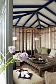 View into open-plan conservatory with comfortable sofa set against glass walls with closed louver blinds