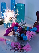 New Year's Eve party - party poppers and lit sparkler in front of coloured glass vases on sideboard