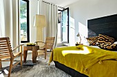 Mustard yellow bedspread on double bed with black headboard next to rustic table and chairs